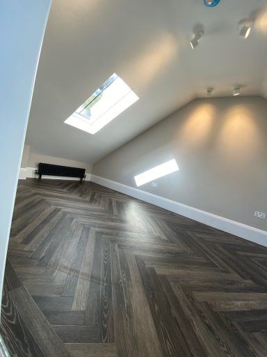Finished loft room with herringbone flooring and skylight